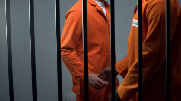 Афро-американец мужчина-заключенный, дающий дозу кавказскому заключенному, наркотрафик
