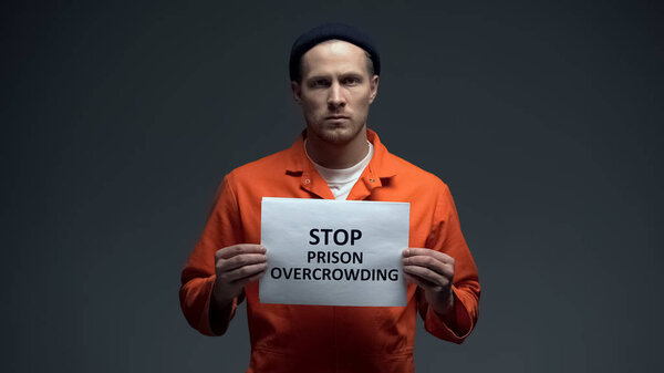 Prisoner holding Stop prison overcrowding sign in cell, life conditions in jails