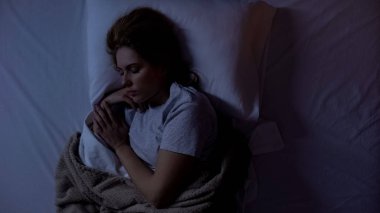 Evde rahat yatakta uyuyan genç kadın, uyku kalitesi, huzur