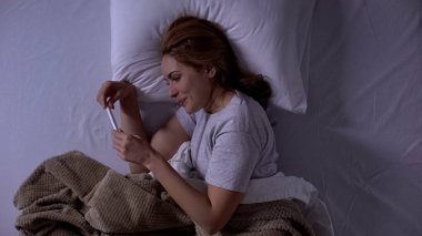 Mutlu bayan yatakta yatan, pozitif test tutan, uzun zamandır beklenen hamilelik seviniyor