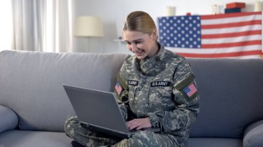 Neşeli Amerikan asker kadın evde dizüstü bilgisayarda görüntülü arama yapma, askeri