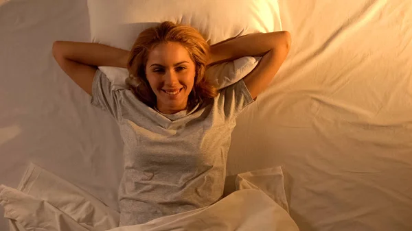 ベッドに横たわって目を覚ます笑顔の女性 新しい日の挨拶 トップビュー — ストック写真