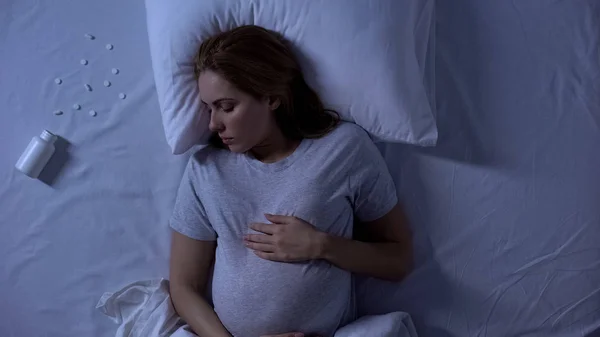 无意识的孕妇躺在床上 药丸中毒 自杀未遂 — 图库照片