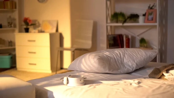 乱雑なベッドの上に横たわる白い目覚まし時計 くしゃくしゃのベッドシーツ 寝過ごしの概念 — ストック写真