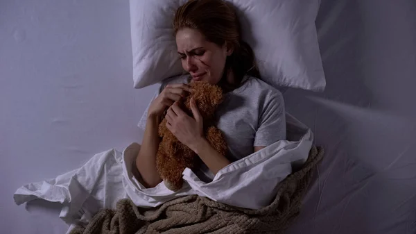 女性暴力受害者拥抱泰迪熊玩具 在床上哭泣 痛苦情绪 — 图库照片