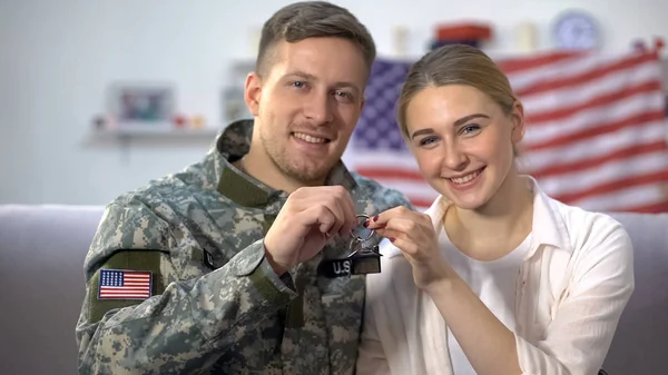 Cheerful US soldier and wife showing apartment keys, military service reward