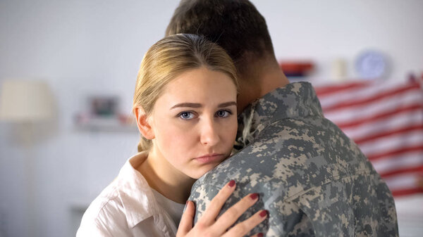 Грустная женщина обнимает солдата, покидающего дом, прощаясь перед военной службой
