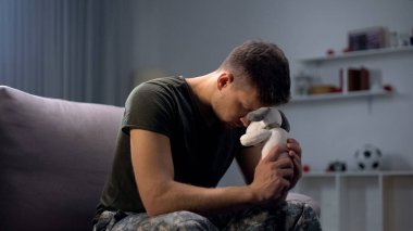 Melankolik erkek asker oyuncak köpek tutan, boşandıktan sonra kayıp çocuk, yalnız