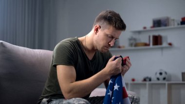 Abd'li asker kanepede oturup ulusal bayrağa, vatanseverliğe ve gurura bakıyor