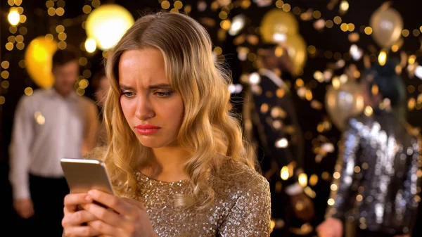 Üzgün şık kadın yazma mesajı akıllı telefon closeup, dans insanlar arka plan