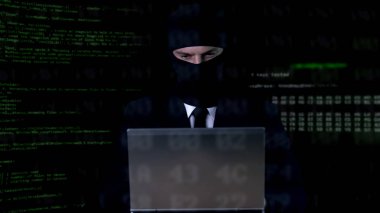 Hacker balaclava dizüstü bilgisayar üzerinde çalışan, yasadışı gizlilik saldırı, veri sızıntısı