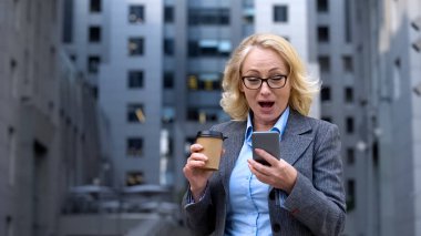 Üst düzey ofis çalışanı iyi haber akıllı telefon, iş uygulaması okuma heyecanlı görünümlü