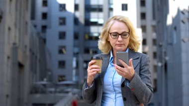 Kahve fincanı tutan akıllı telefon iş haberleri okuma bölüm ciddi başkanı