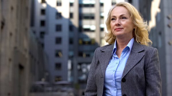 Beautiful mature business lady standing outside office building, career success