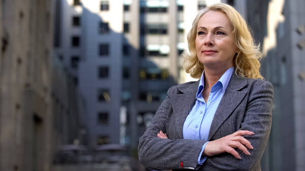 Confident female boss with folded arms outside office, career motivation, job