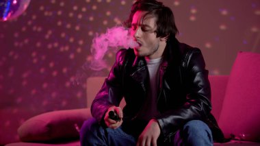 Genç adam vaping e-sigara stres, gece kulübü partide rahatlatıcı rahatlatmak için boşta