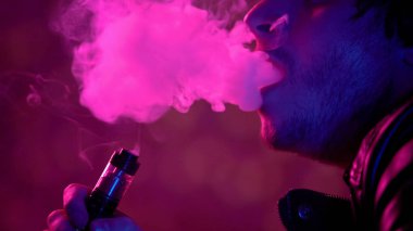 Adam vaping e-sigara dumanı, sağlıksız alışkanlık bulutlar exhaling karanlıkta
