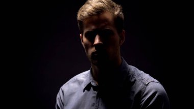 Siyah arka planda kameraya bakan utangaç gölgeli adam, mens sağlık, suç