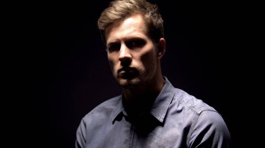 Karanlık arka planda aydınlatıcı genç adam, şüpheli suç, sorgulama