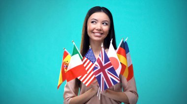 Farklı ülkelerbayrakları tutan gülümseyen Asyalı kadın, uluslararası işbirliği