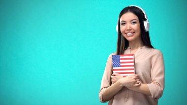 Kız öğrenci kulaklık amerikan İngilizce ses dersleri dinleme, elinde kitap