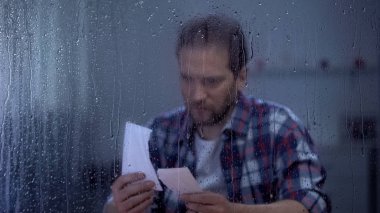 Üzgün orta yaşlı adam yırtık fotoğraf, kayıp karısı iki parça bir araya koyarak