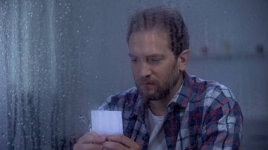 Üzgün boşanmış adam yağmurlu bir günde aile fotoğrafı bakarak, kayıp karısı ve çocukları