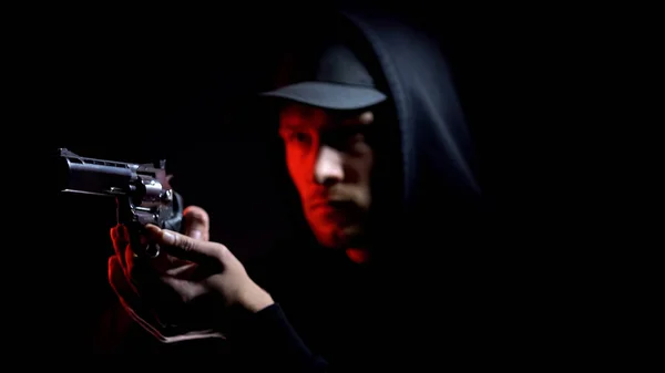 暗い背景 武装強盗 犯罪に対して銃を狙うパーカーで男性泥棒 — ストック写真