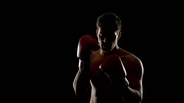 戦いの準備をするボクシンググローブの強い男 ジムの黒い背景でトレーニング — ストック写真