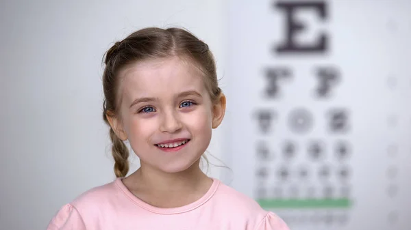 アイチャート上の視力テストの後に笑う愛らしい子供の女の子 健康的な視力 — ストック写真