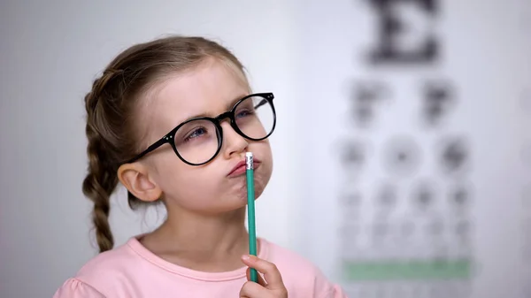 眼鏡をかけたペンシブスマートな女の子 クリニックで目のチャートでビジョンをテスト — ストック写真