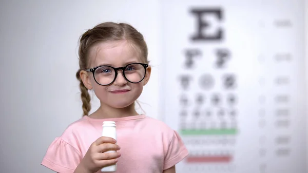 視力を改善するためにおいしいビタミンシロップを飲む眼鏡の陽気な子供 — ストック写真