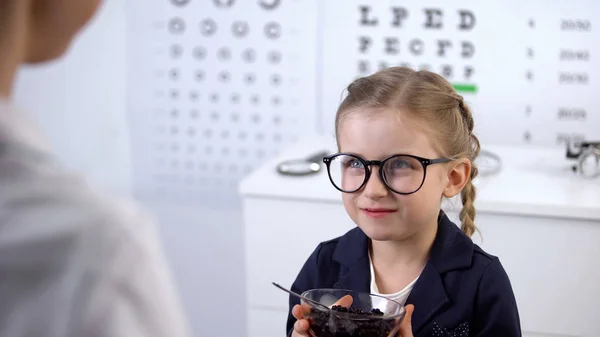 かわいい女の子にブルーベリーを与える眼科医 目のための自然なビタミン — ストック写真