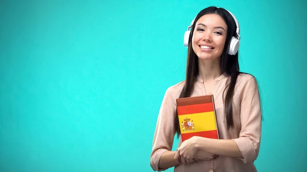 Dziewczyna Słuchanie Hiszpańskich Lekcji Audio Zestawie Słuchawkowym Książka Rękach Tłumaczenia — Zdjęcie stockowe