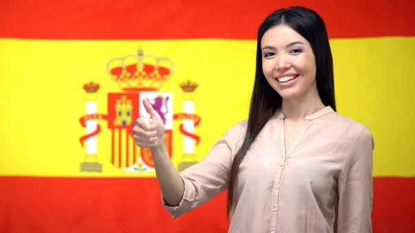 Lächelnde Asiatin Zeigt Daumen Hoch Geste Vor Spanischem Flaggenhintergrund — Stockfoto