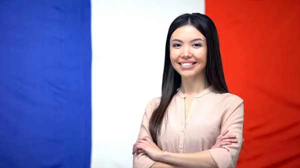 Cheerful Asian Girl Standing Hands Crossed French Flag Background — Stock Photo, Image