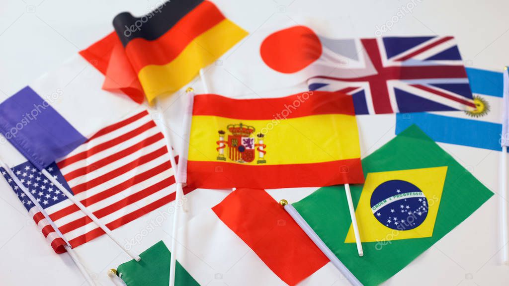 Flags of different countries lying on white table, international cooperation