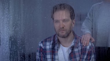 Depresif kocasının omzunda el ele tutuşan karısı, aile desteği, yağmurlu gün