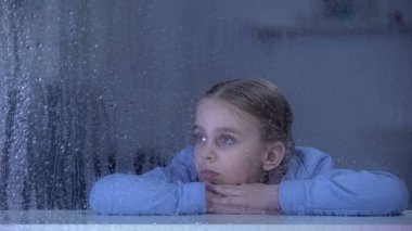 Yağmurlu günde pencere pervazı yatan kız, ev hayali nde yetim çocuk, yalnızlık