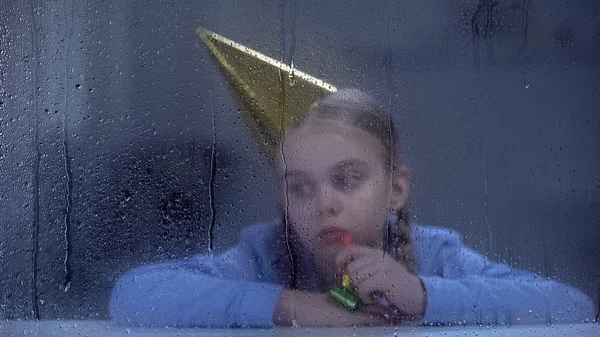 Smutna Dziewczyna Imprezie Kapelusz Dmuchawą Oknem Deszczowej Zapomniane Przez Rodziców — Zdjęcie stockowe