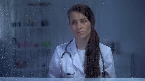 Mujer Triste Médico Mirando Través Ventana Lluviosa Trabajo Estresante Concepto —  Fotos de Stock