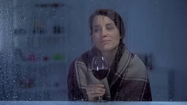 阴冷的女人在毯子里喝着酒在雨窗后面 寒冷的夜晚 — 图库照片