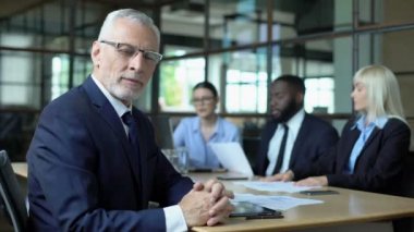 Yaşlı şirket müdürü kamera arıyor, ofis arkadaşları strateji tartışıyor