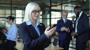 Gülümseyen kadın yönetici akıllı telefonda e-posta okuma, iş haberleri uygulaması kaydırma