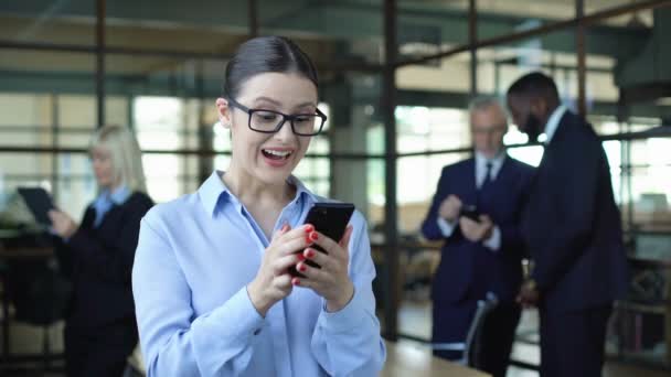 Gelukkig bedrijf werknemer tonen ja gebaar lezing smartphone bericht, succes — Stockvideo