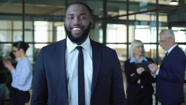 Uomo d'affari africano sorridente in tuta armi pieghevoli, lavoro d'ufficio, successo aziendale — Video Stock