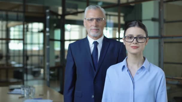 Young woman and mature man folding arms looking camera, trainee and boss, team — Stock Video