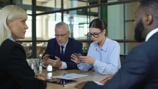Empresário e mulher conversando com parceiros indiferentes rolando smartphones — Vídeo de Stock
