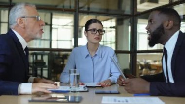 Kulaklarını kapatan stresli kadın işçi, ofis çalışanlarını tartışmaktan yorulmuş gibi hissediyor