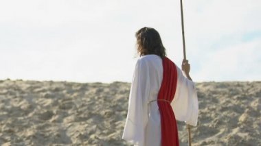 İsa cüppe ve kuşak kumlu tepede yürüyüş personeli ile, yardım eli germe